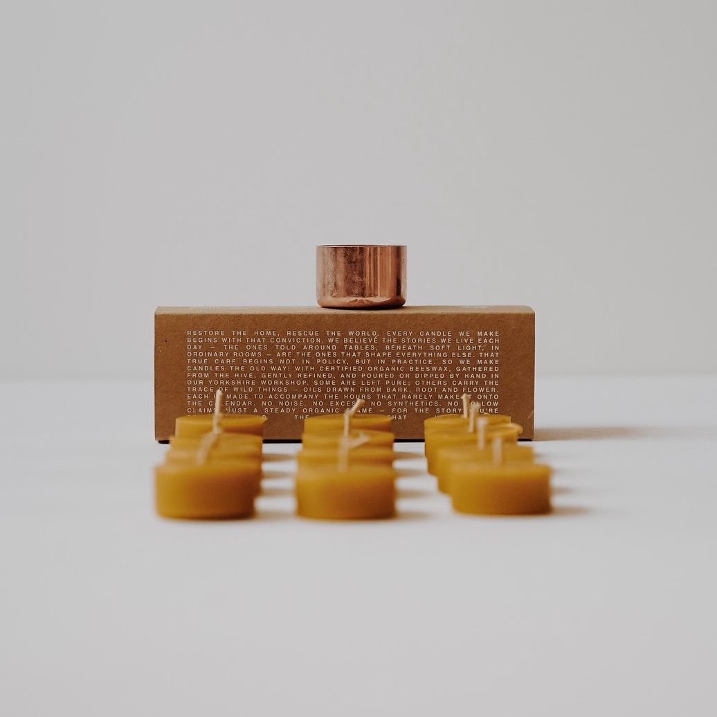 Twelve certified organic beeswax tealights with cotton wicks beside a solid reusable copper cup